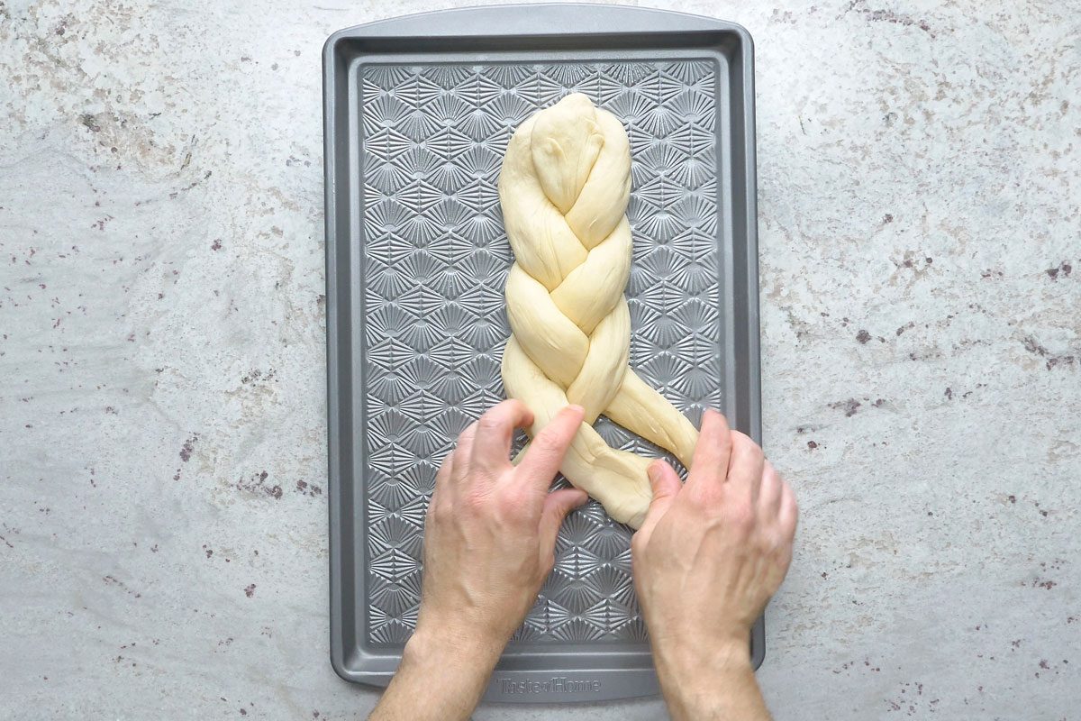 Overhead shot; For each loaf; braid 3 ropes together on a greased baking sheet; pinch ends to seal and tuck under; cover with kitchen towels; let rise in a warm place until doubled about 50 minutes; Preheat oven to 375 degree; grey surface;