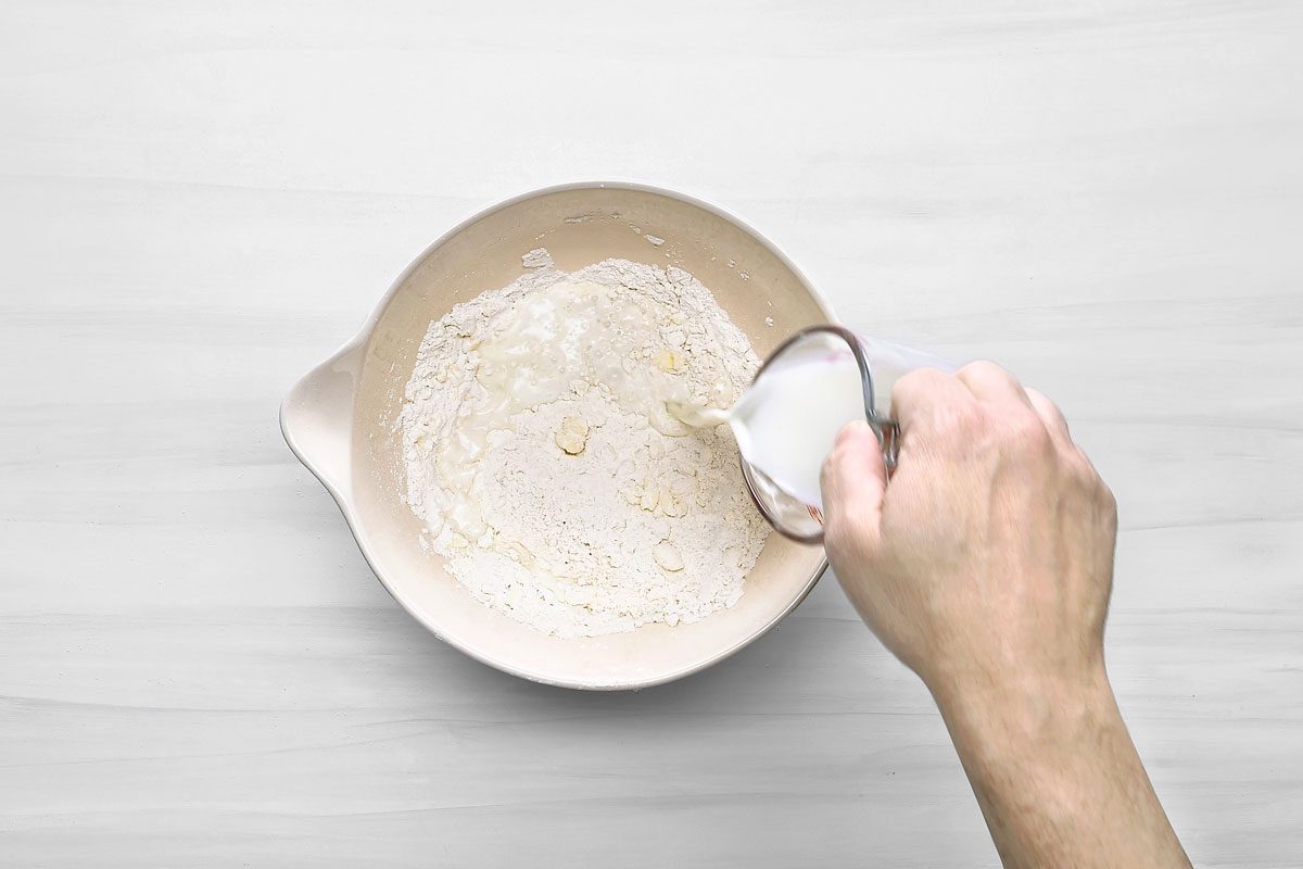 Overhead shot of a large bowl whisk flour; baking powder and salt; cut in butter until mixture resembles coarse crumbs; add milk; stir just until moistened; wooden surface