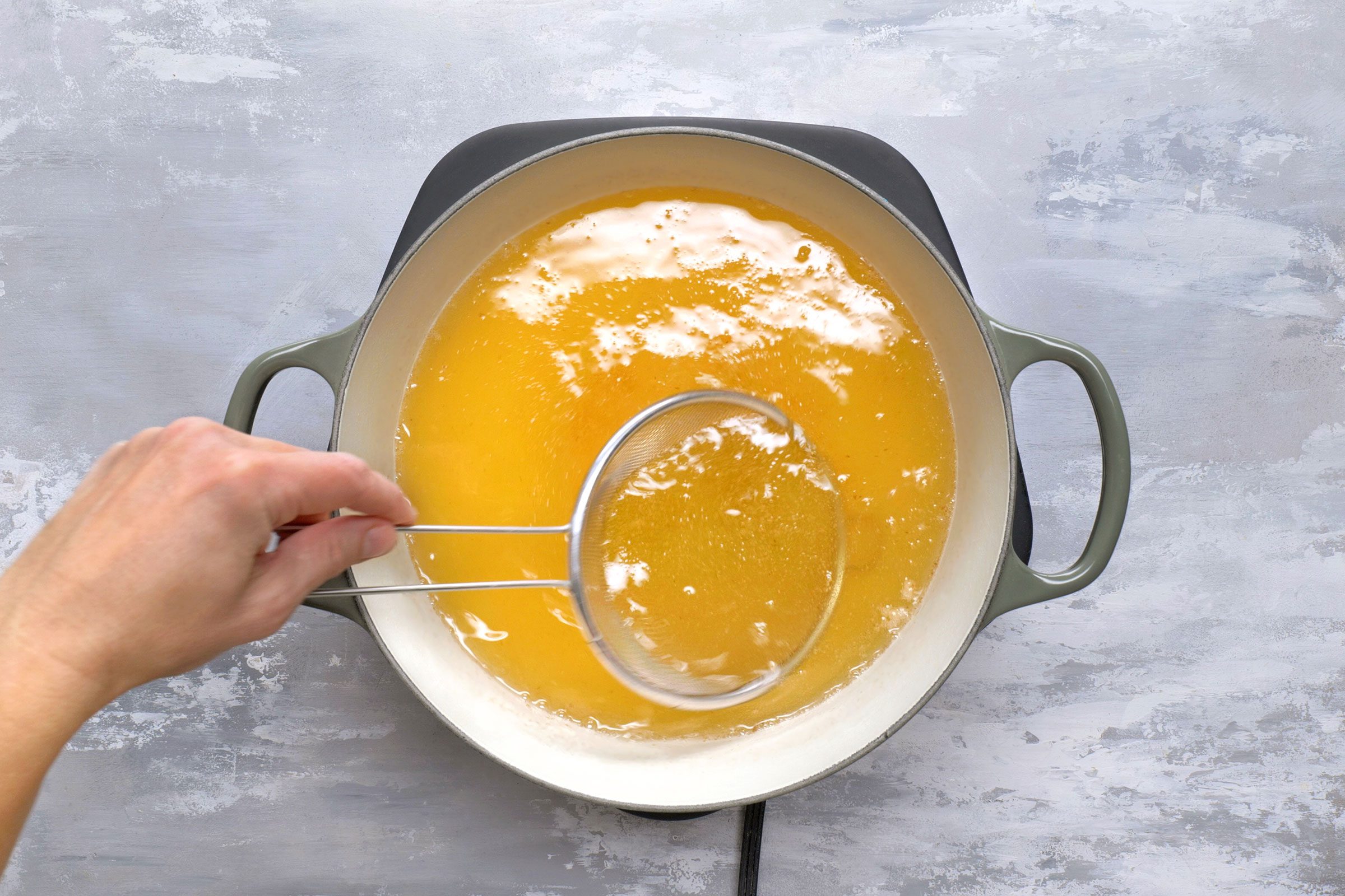 Removing fried bits from oil using a mesh strainer 
