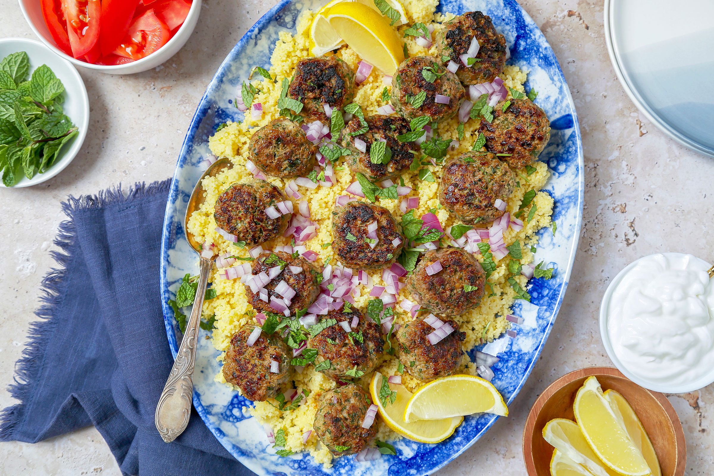 Kofta Meatballs in a plate with some veggies, lemon and greek yoghurt on side