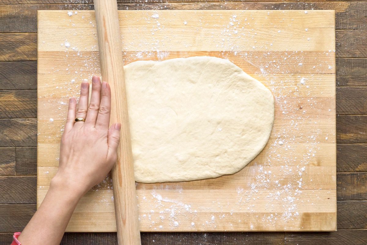 dough being rolled into half inch thickness portion