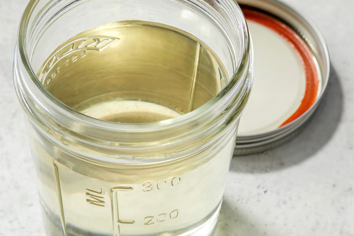 Close up shot of Homemade Simple Syrup; in a container with a tight-fitting lid; marble surface