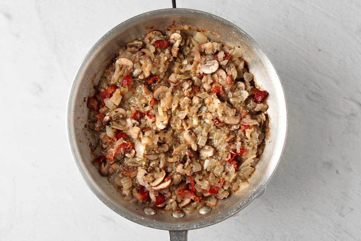 chopped onions, bacon, breadcrumbs and parsley being cooked together with butter, mushrooms, salt, pepper and nutmeg