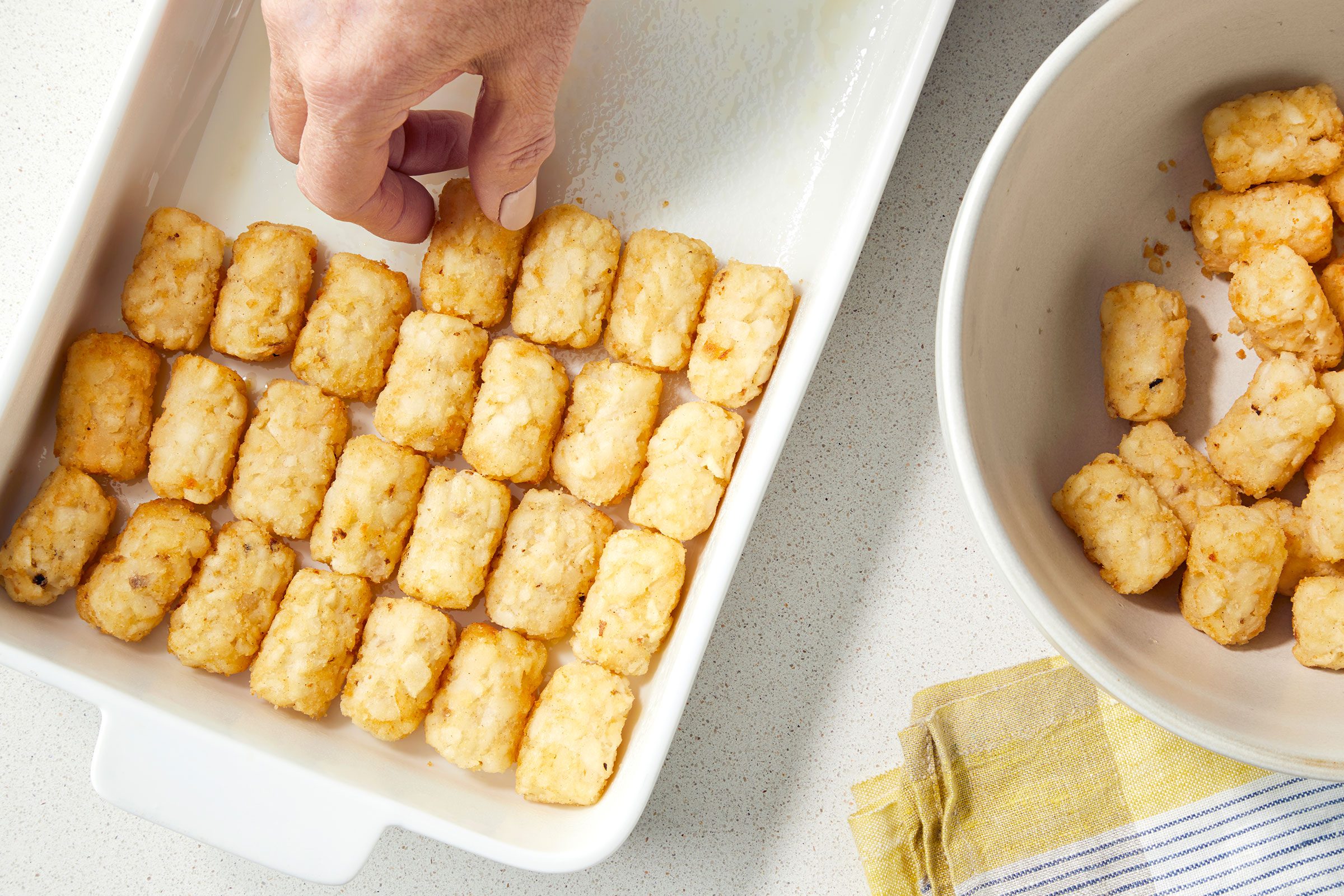 Lining the bottom of greased baking dish with Tater Tots