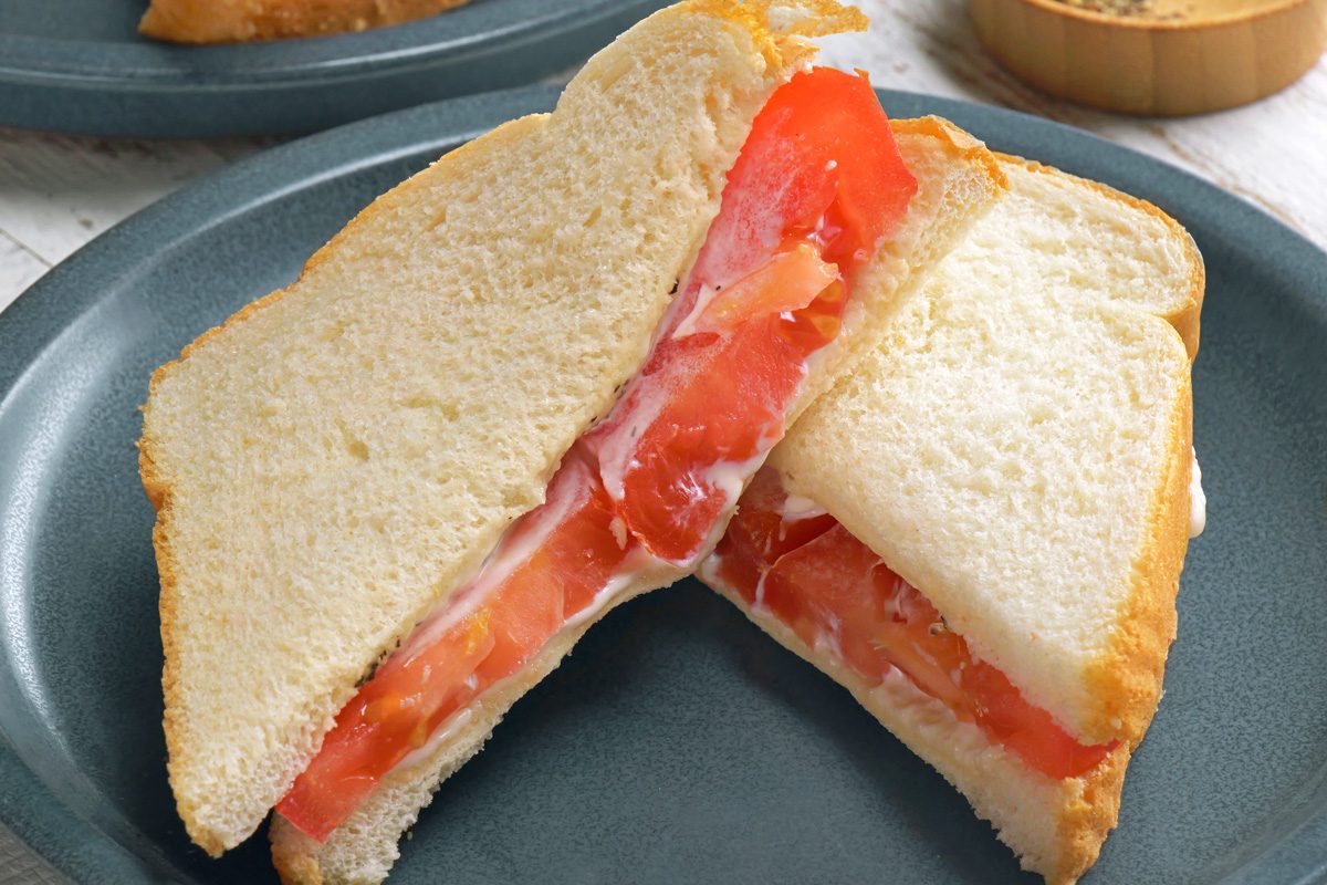 Close shot of Tomato Sandwich; serve on plates; white wooden surface;
