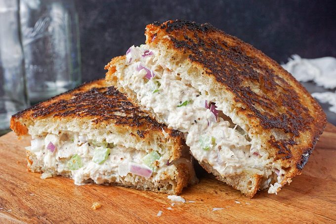 A tuna melt cut in half on a wooden cutting board