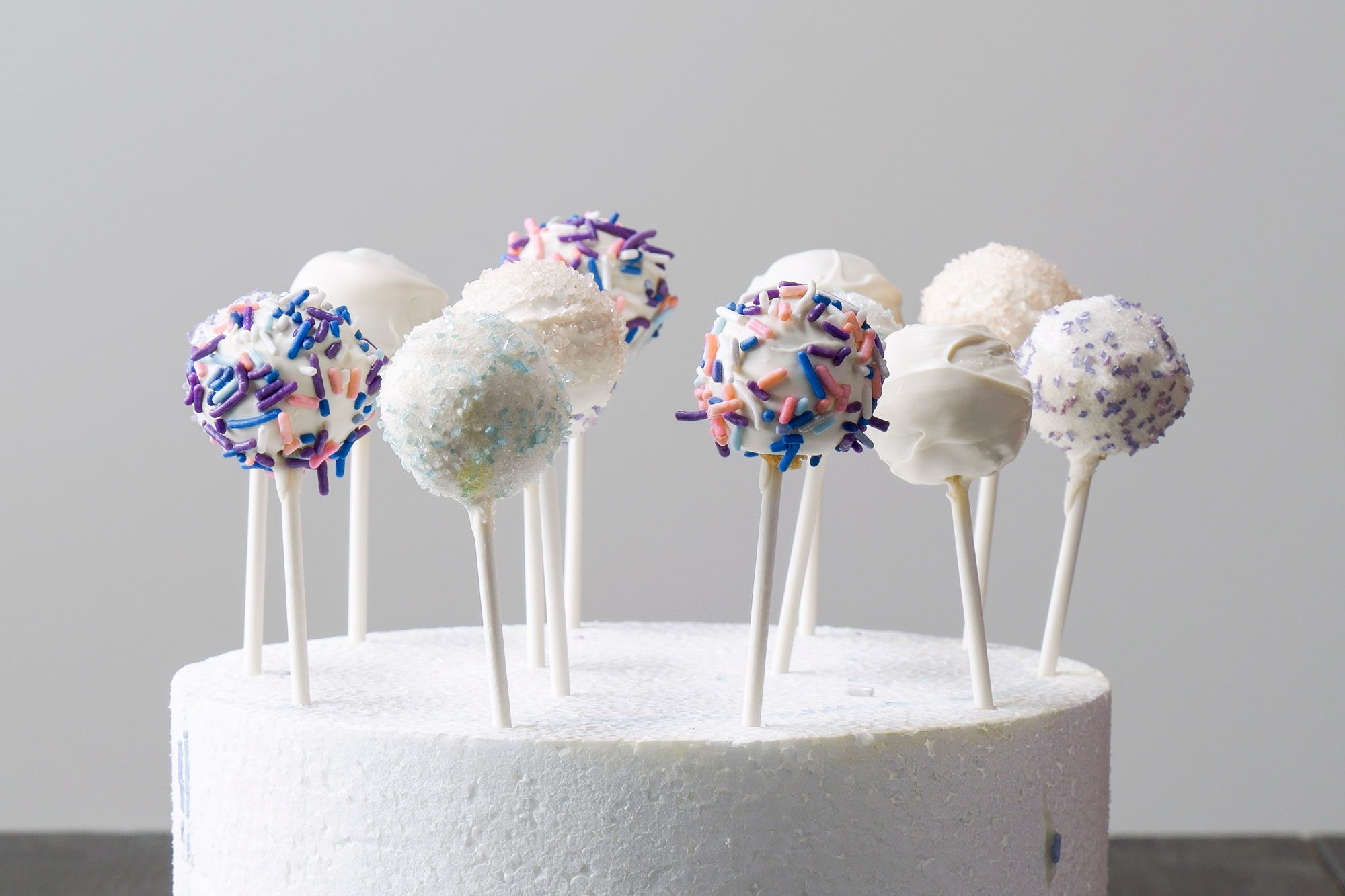 horizontal shot of cake pops displayed on top of a circular white thermocol stand
