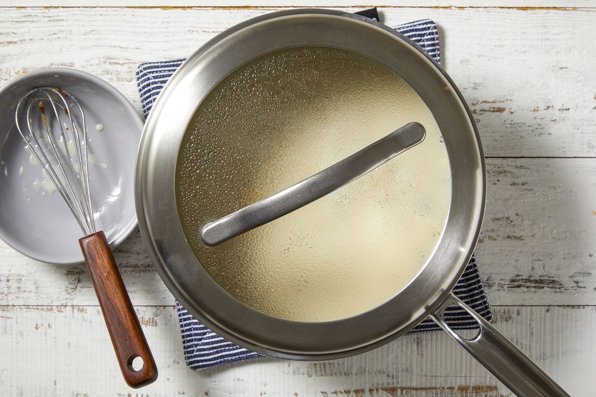 Overhead shot of remove from heat; let stand covered 15 minutes to allow flavors to blend; whisk tool; wooden surface;