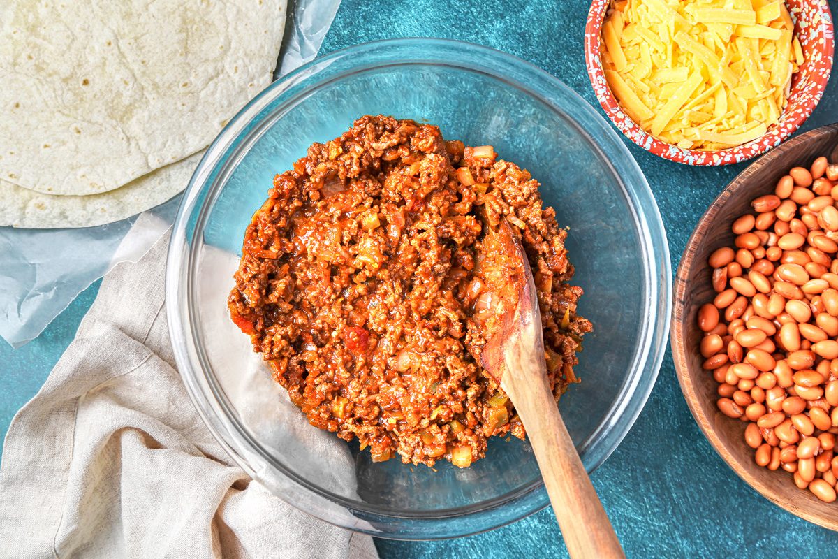 cooked beef and onion with salsa seasoning in a large bowl
