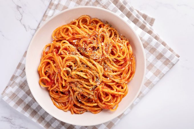 Spaghetti with tomato sauce on white background.
