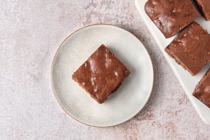 Overhead shot of Easy Gluten Free Brownies; place on white tray; served on a small plate; light brown marble surface;