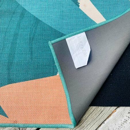 Blue and orange ruggable outdoor rug folded over revealing black rug pad