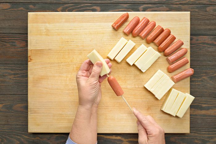 Threading one piece of hot dog and cheese each onto skewers