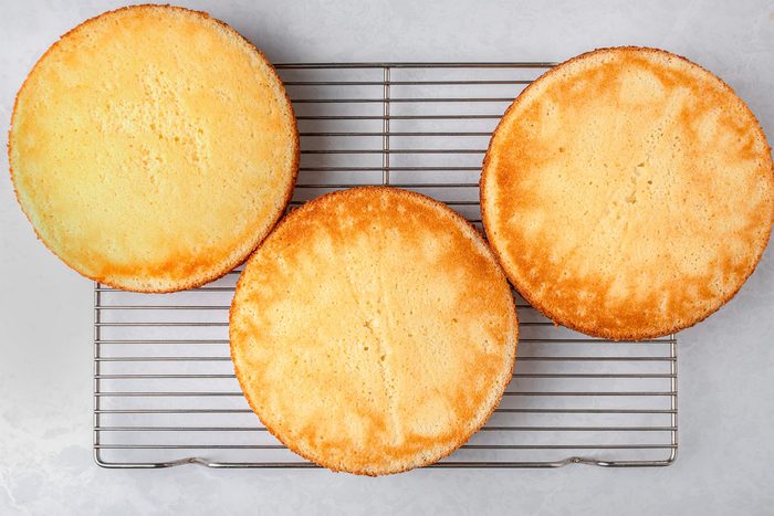 Baked lemon cakes on a wired rack kept on top of a grey marbletop