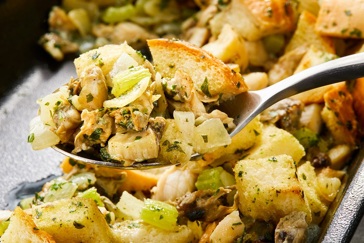A close-up of a spoonful of stuffing, featuring chunks of bread, onions, celery, and herbs. 
