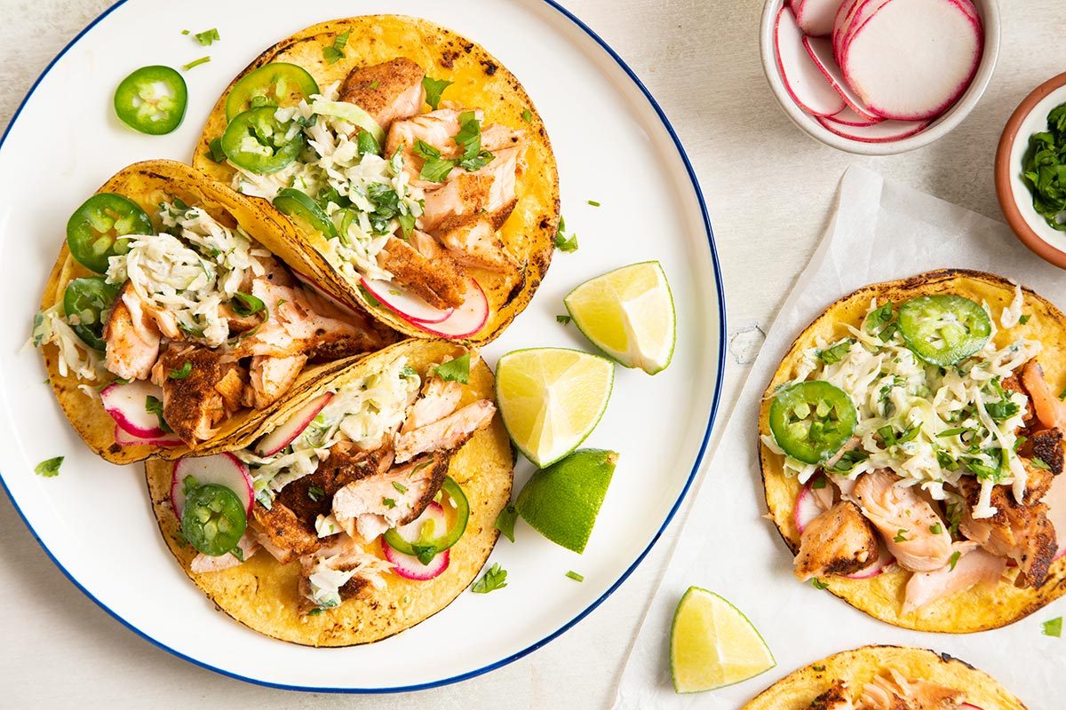 Salmon taco served on a plate and lime wedges on the side.