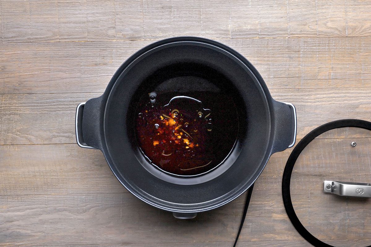 overhead shot of a black pot with a glass lid on a wooden surface
