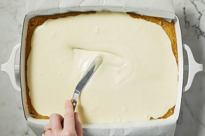 Applying cheesecake filling on chilled crust for Strawberry Cheesecake Bars