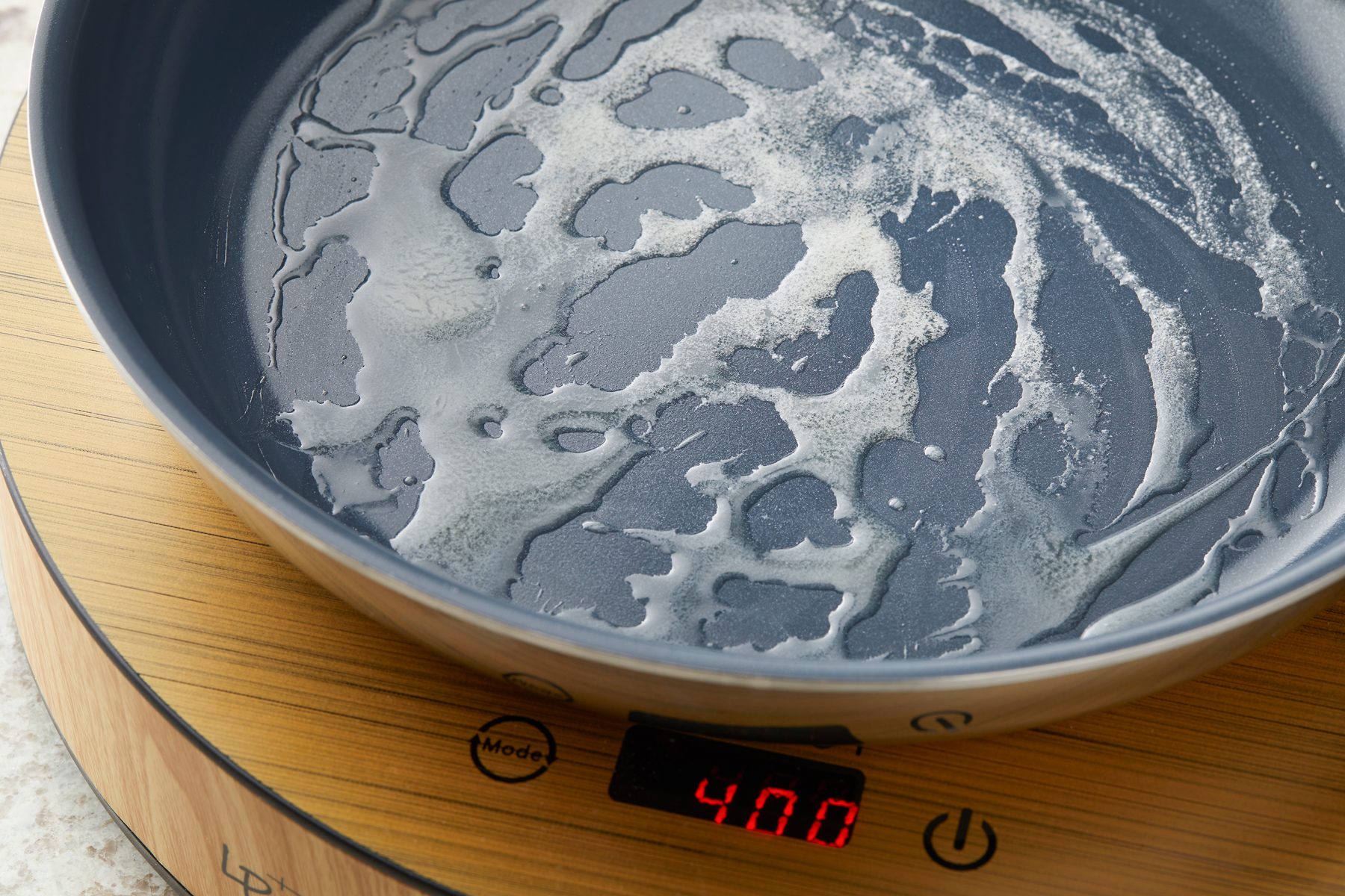 Close up shot of heat butter in a large skillet over medium heat; induction; marble surface;