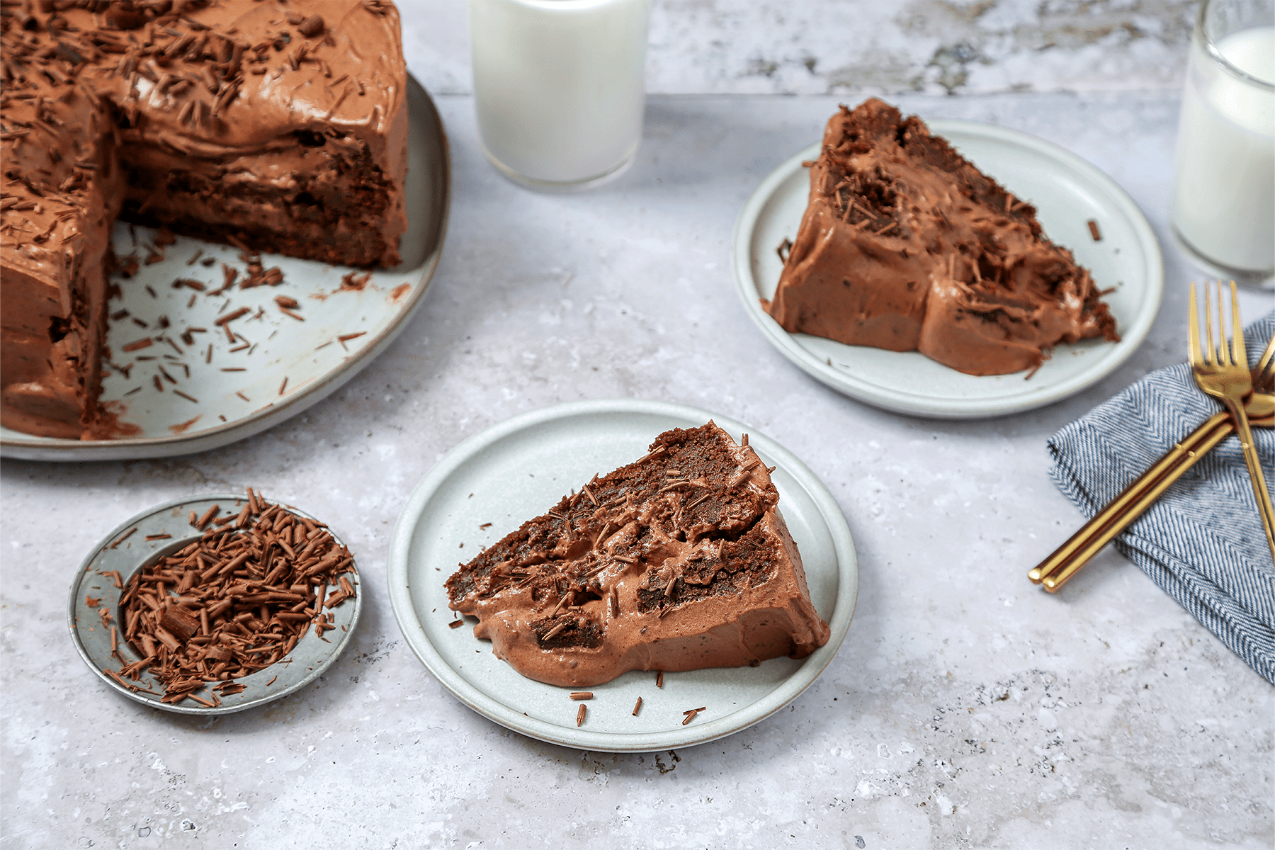 A slice of Brownie Cake served in a plate with gold forks