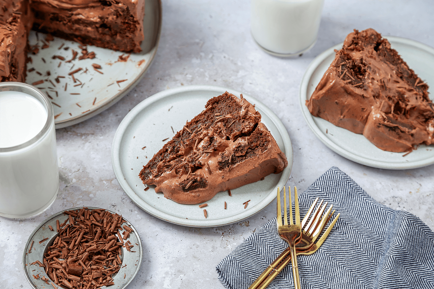 A slice of Brownie Cake served in a plate with gold forks