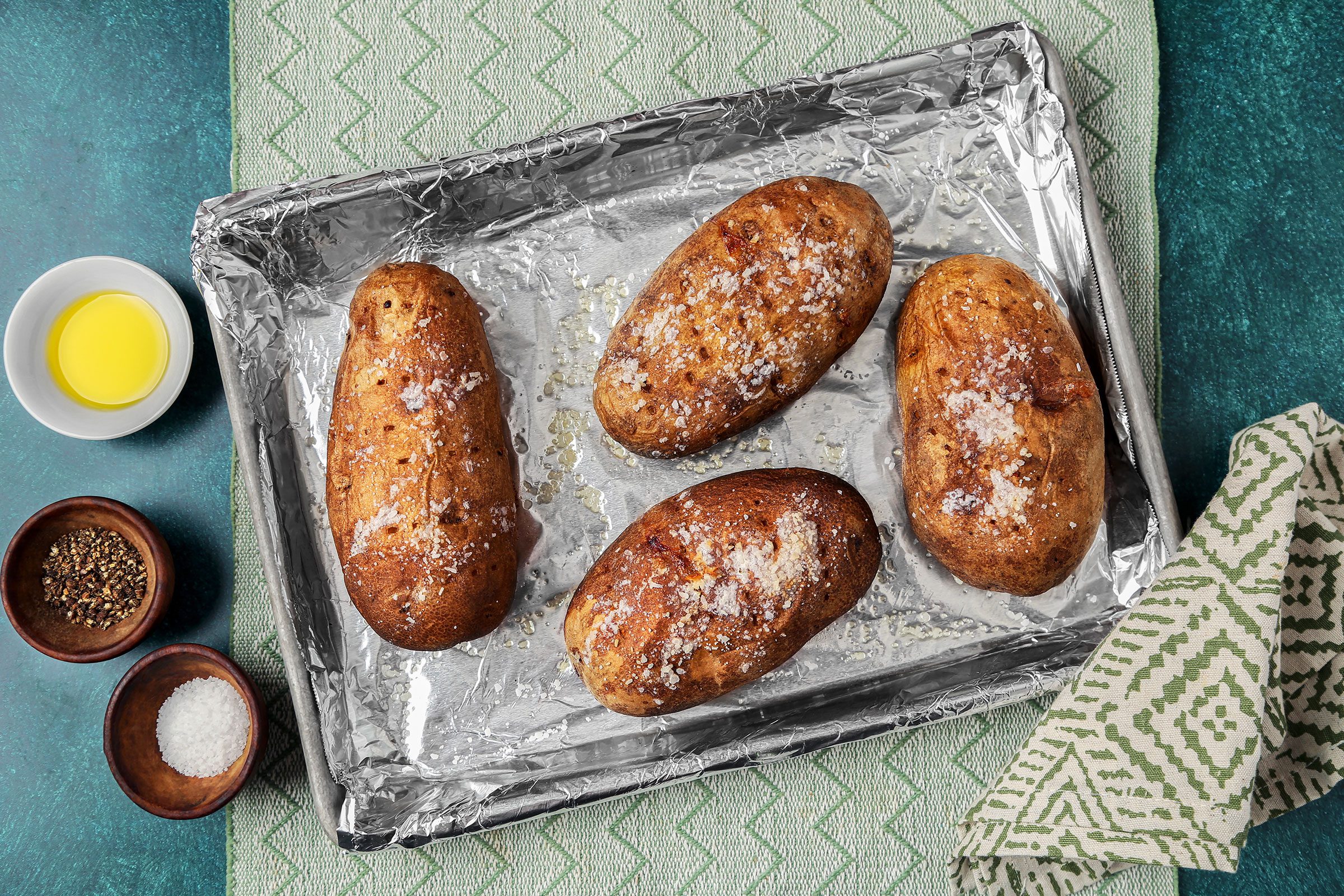 Pierced potatoes with salt on a foil lined baking pan