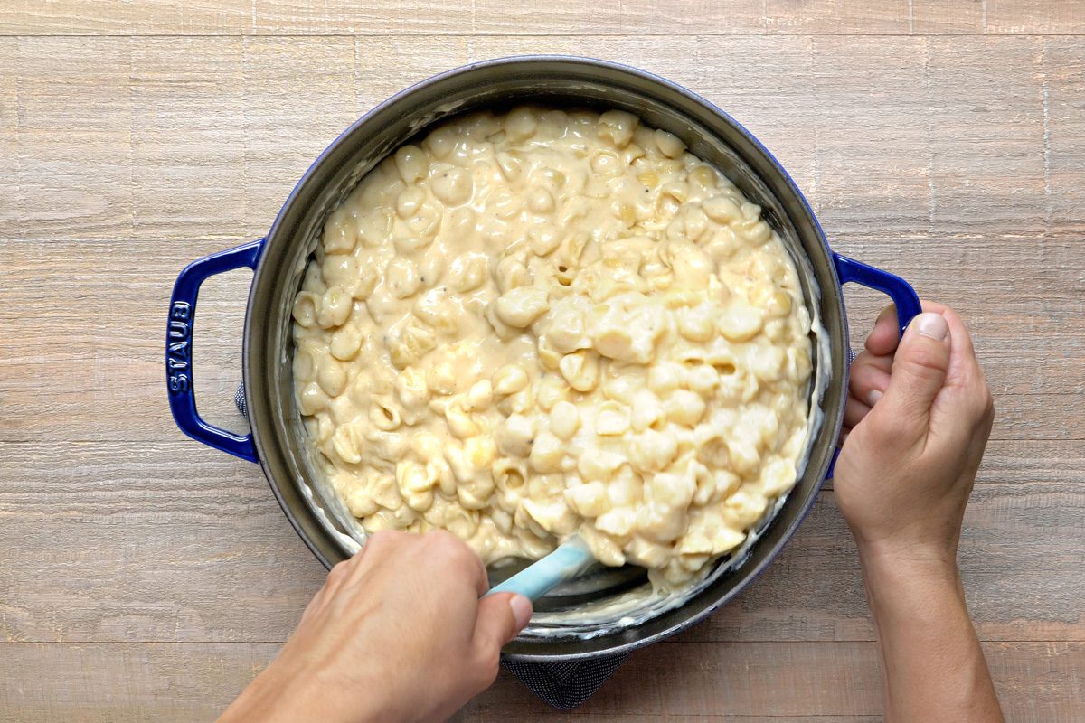 cheese sauce being mixed with pasta