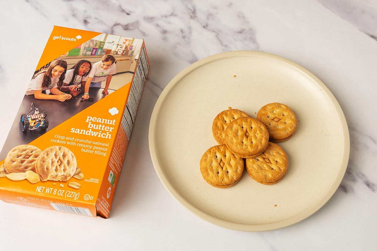 Package of Peanut Butter Sandwich Girl Scout Cookies next to several cookies on a plate