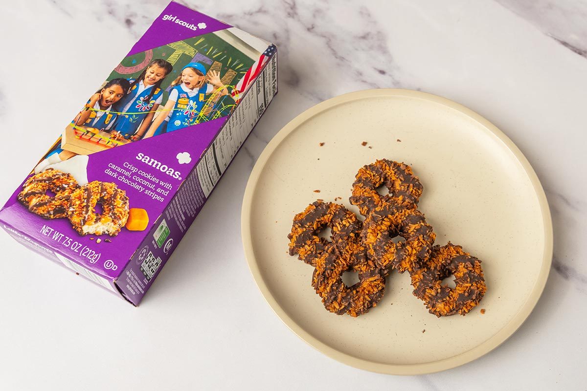 Package of Samoas Girl Scout Cookies next to several cookies on a plate