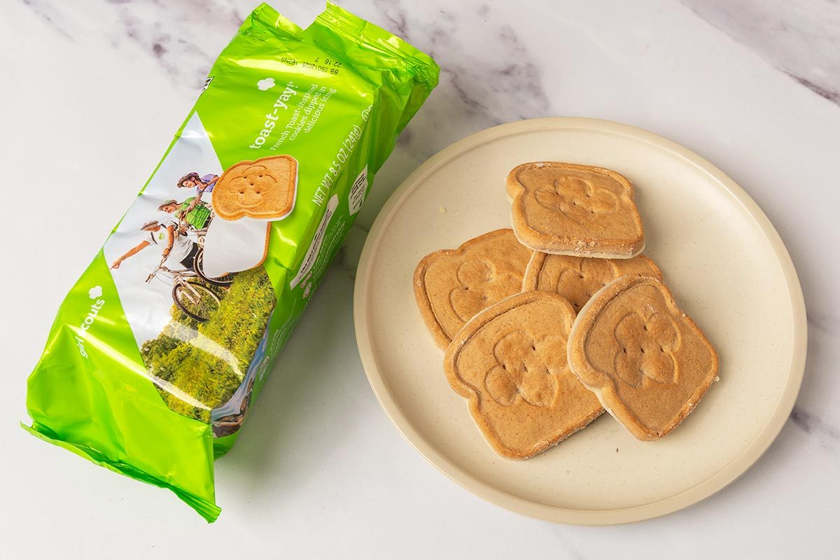 Package of toast-yay Girl Scout Cookies next to several cookies on a plate