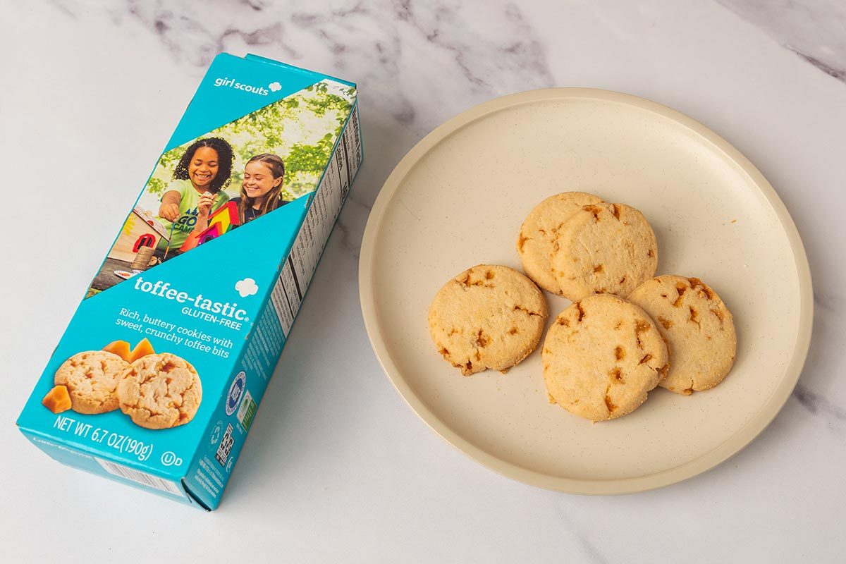 Package of toffeetastic Girl Scout Cookies next to several cookies on a plate