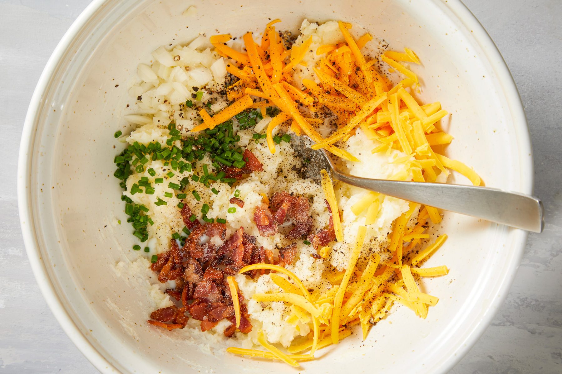 Stir in the milk, bacon, onion, chives, salt, pepper and 1/2 cup cheese.