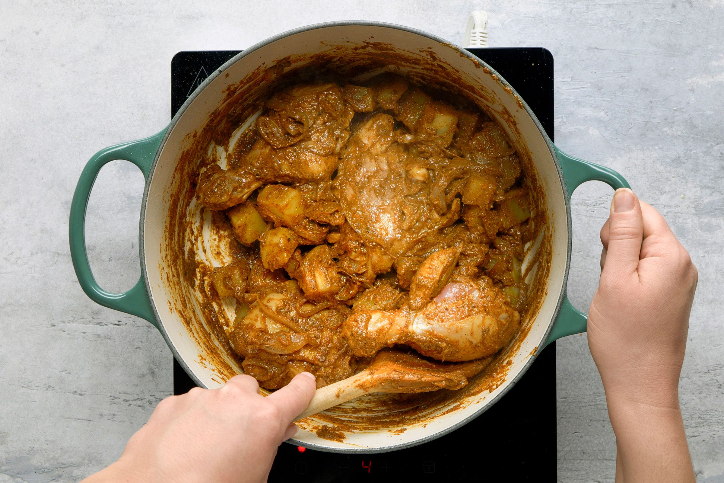 Adding the chicken and marinade to the pot of caramelized onions and stirring them