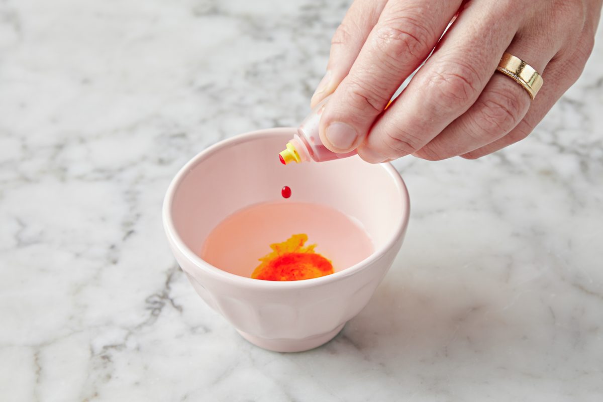 food colouring being added to water in a small bowl