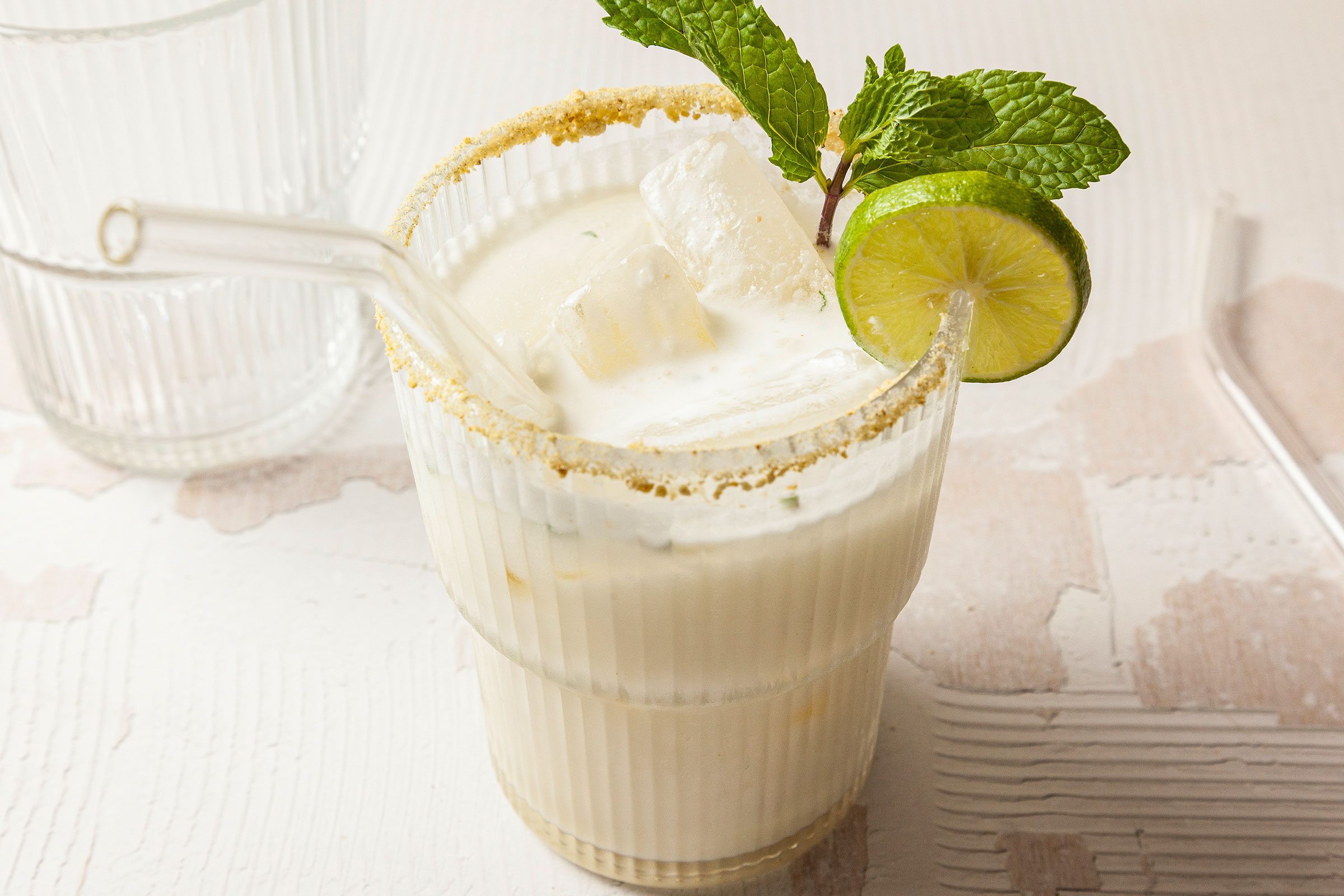 Key Lime Mojito in a glass with a glass straw and slice of lemon and few mint leaves