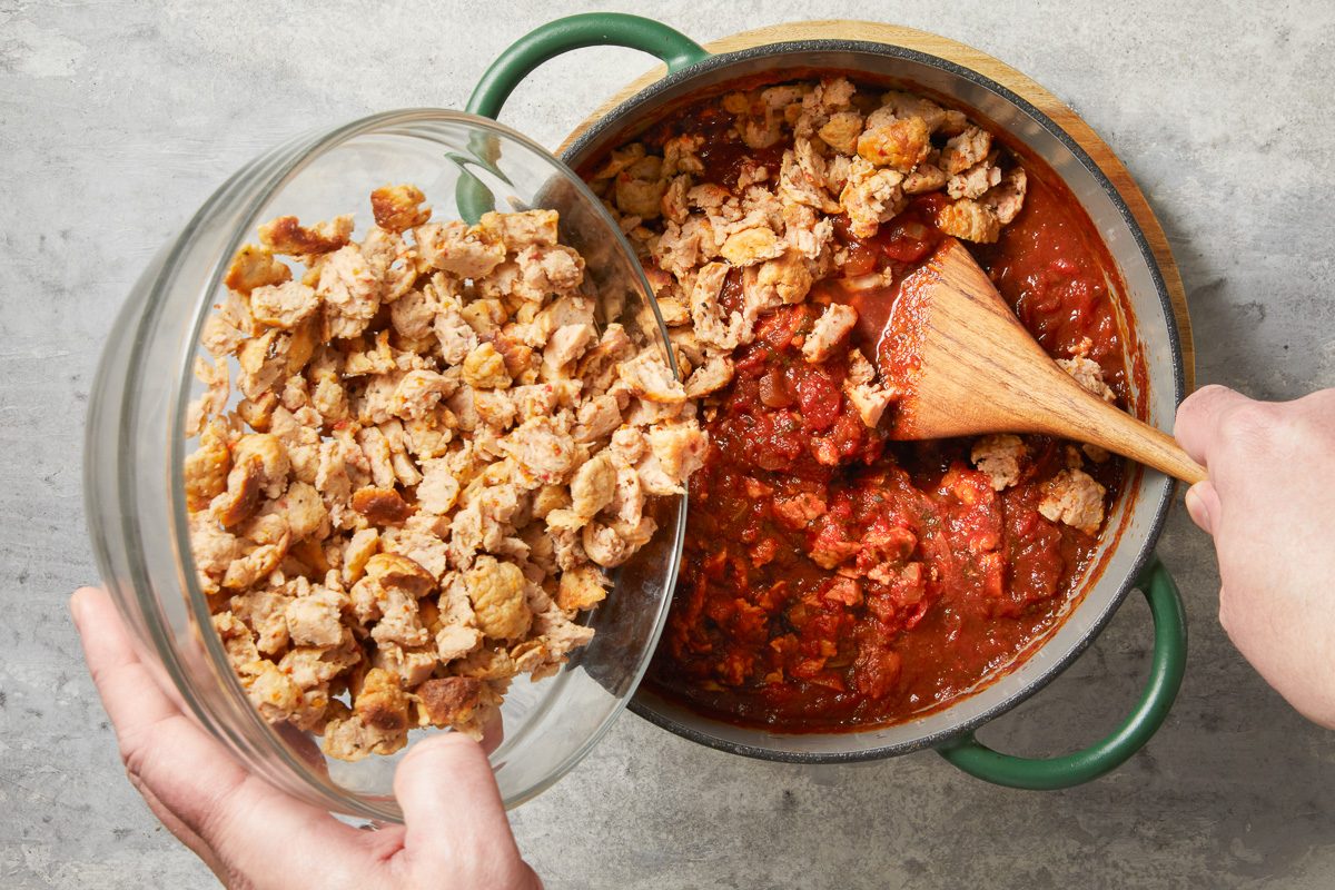 adding meatball crumbles into sauce