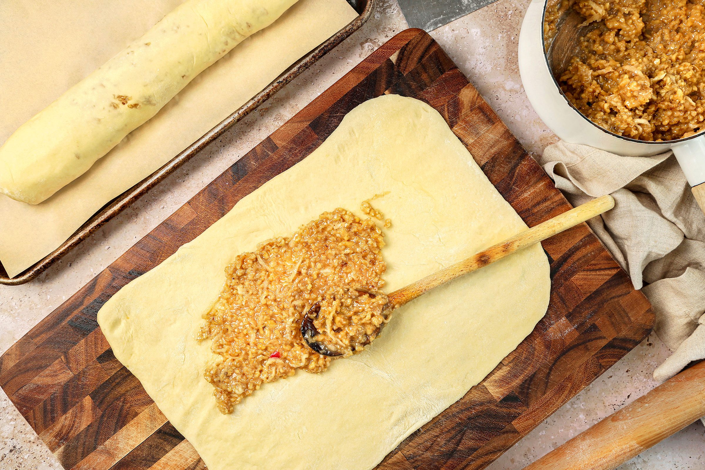 Putting the filling between the four strips, spreading it to within 1/2-inch of the edges with a rolled dough on side