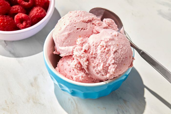 Raspberry ice cream served in a blue cup.