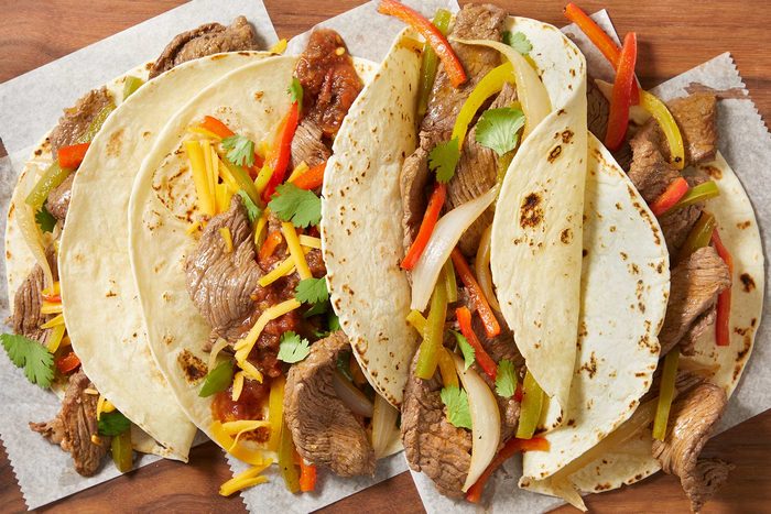 Overhead shot of Slow-Cooker Fajitas kept on top of paper napkins on a wooden table.