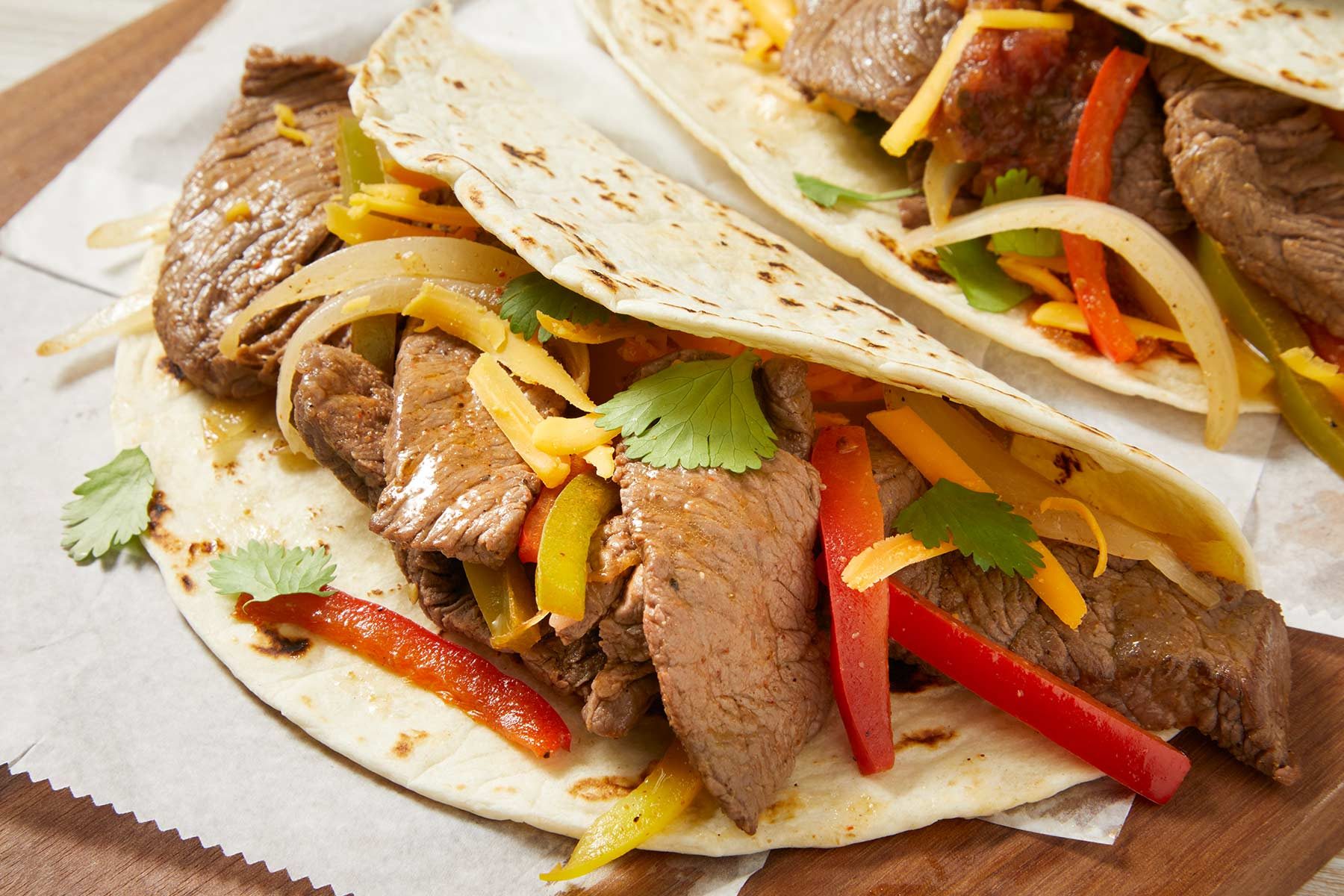 Close up 3/4 shot of Slow-Cooker Fajitas kept on paper napkins on a wooden table.