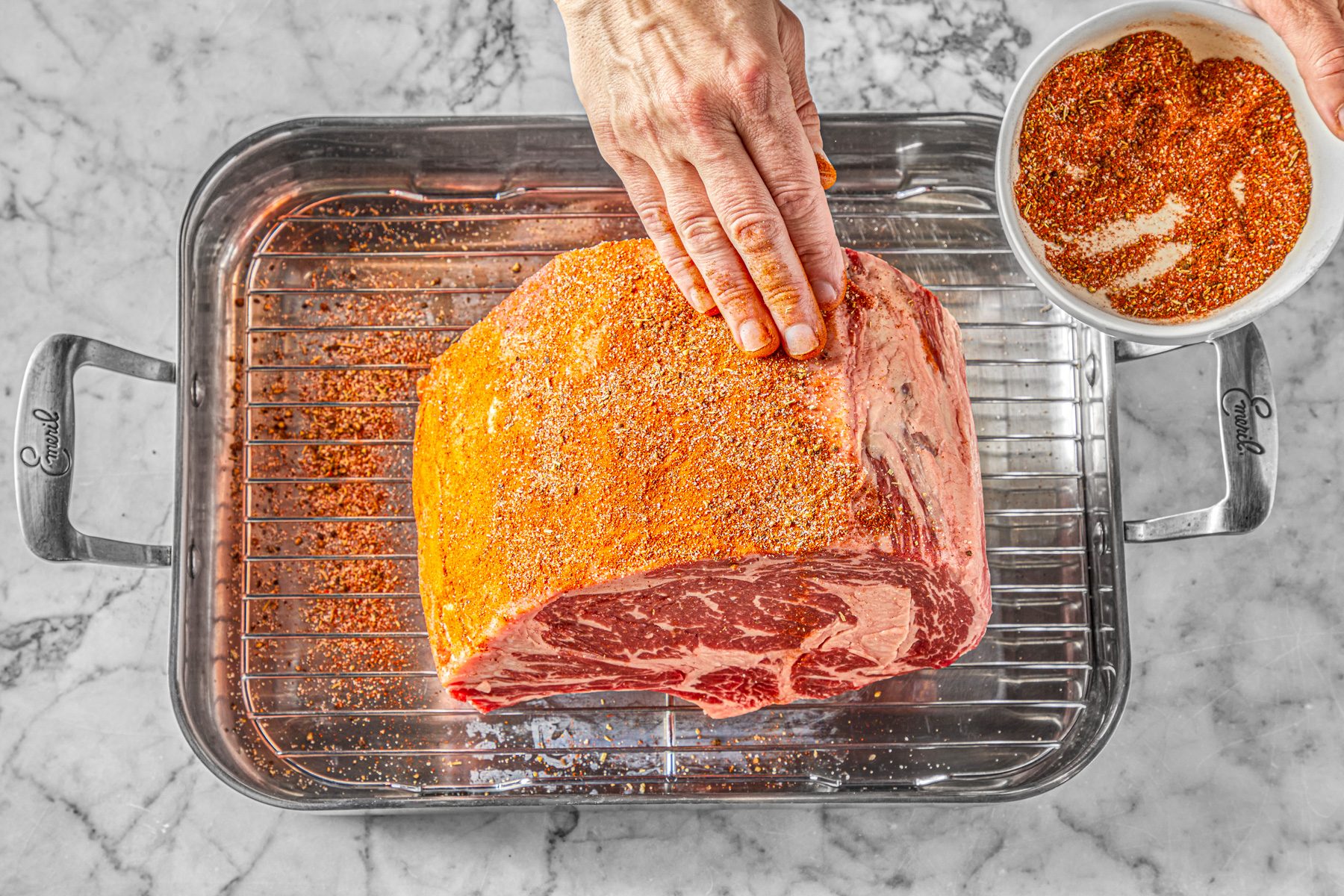 Overhead shot a small bowl mix the first 5 ingredients; Preheat oven to 325 degree; Place roast in a roasting pan; fat side up; rub with seasoning mixture; Roast 2-1/4 to 2-3/4 hours or until meat reaches desired doneness; Remove roast from oven; tent with foil; Let stand 15 minutes before carving; all set on a marble surface;