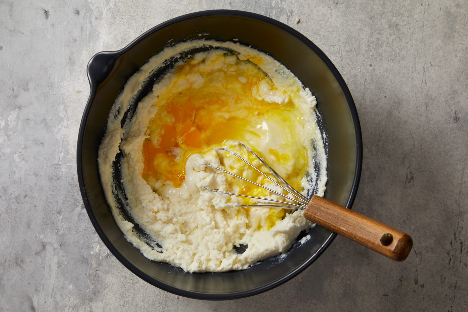 Overhead shot; Reserve 2 tablespoons beaten egg for egg wash; place remaining egg in a large bowl with ricotta; beat until smooth; whisk tool; marble surface;