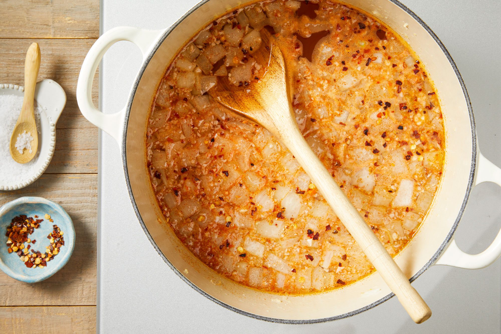 Add garlic, vegetable broth and water; bring to a boil. Add salt, paprika and crushed pepper flakes;