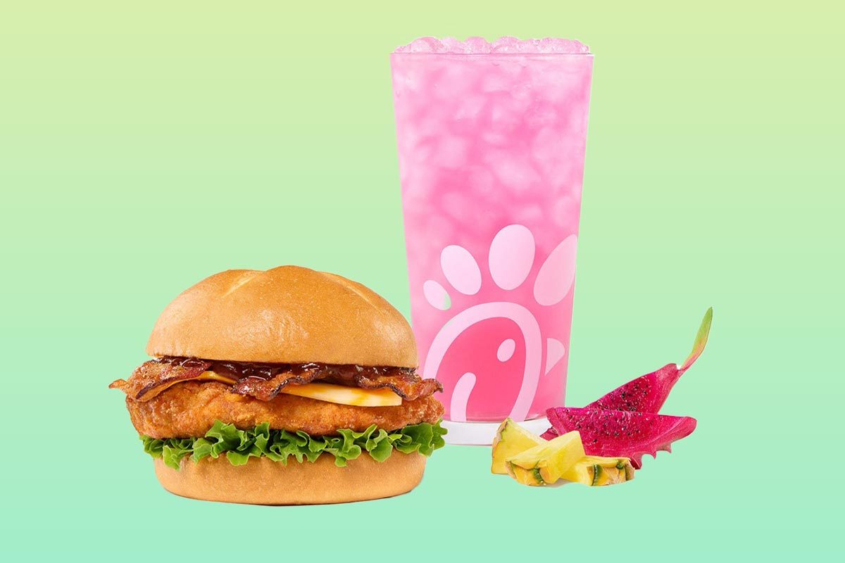 Smokehouse BBQ bacon sandwich with dragonfruit lemonade and pieces of dragonfruit on a green background