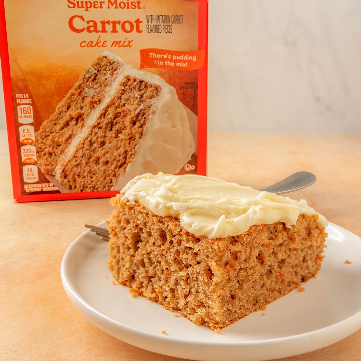 Betty Crocker slice of carrot cake with cream cheese frosting on a white plate with the box in the background