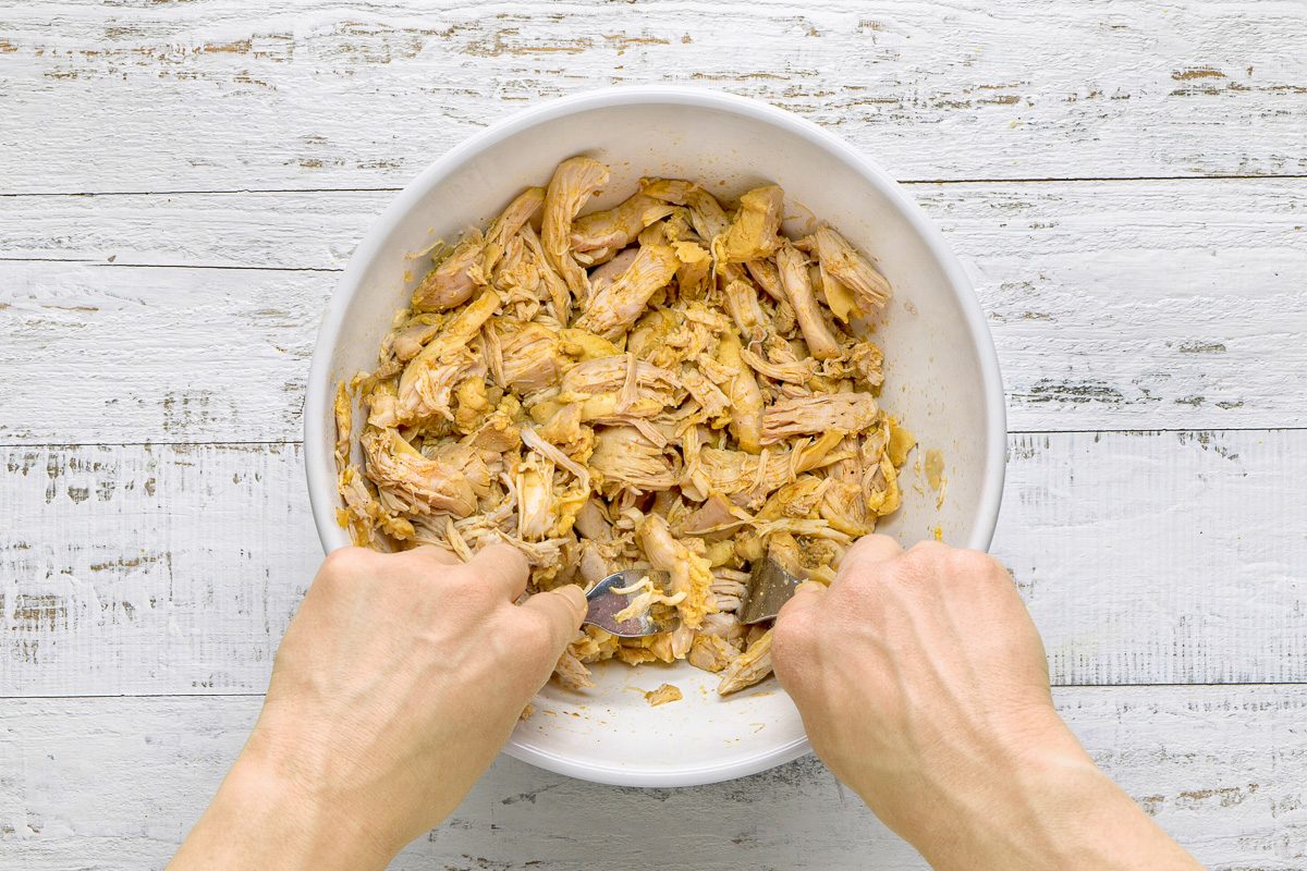 chicken being shredded with two forks