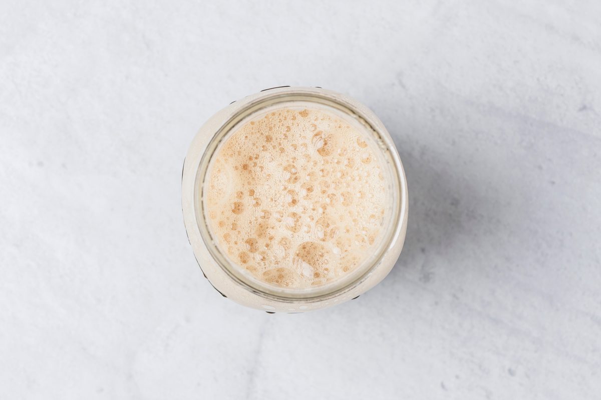 Overhead shot of Fill a Mason jar with ice; Top with brown sugar syrup and espresso; Seal with lid and shake until ingredients are combined and mixture is slightly frothy; marble surface;