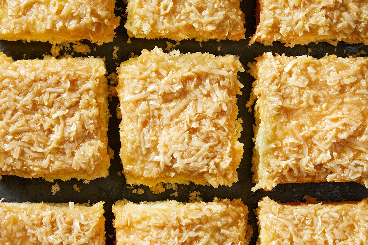 Nine square pieces of flaky, golden pastries with a shredded topping are closely arranged in a grid pattern.