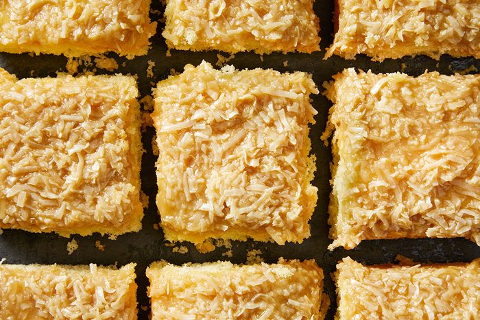 Nine square pieces of flaky, golden pastries with a shredded topping are closely arranged in a grid pattern.