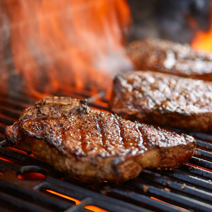 grilling steaks on flaming grill and shot with selective focus